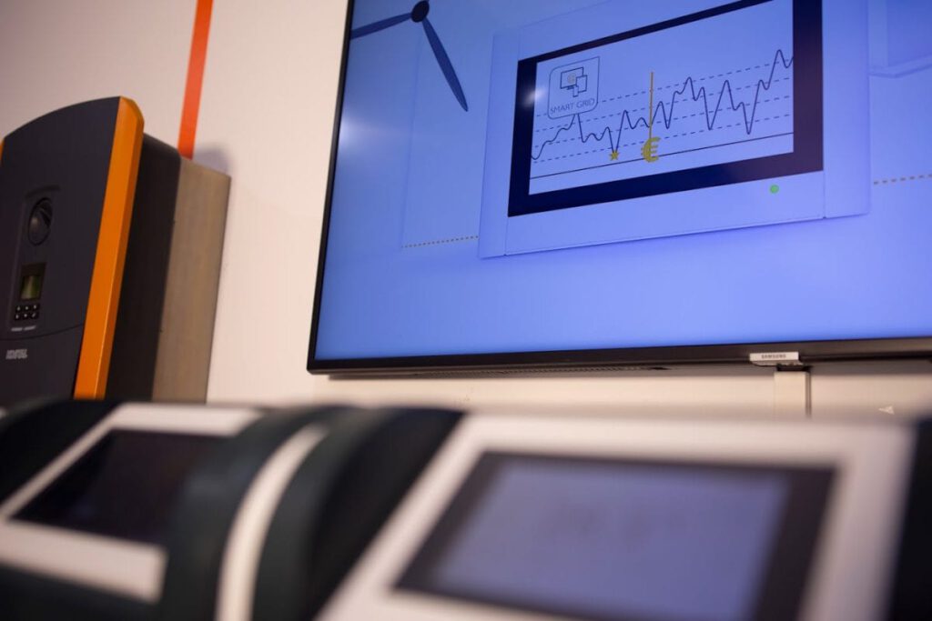 zwei Geräte mit einem kleinen Monitor und einem großen Bildschirm im Hintergrund