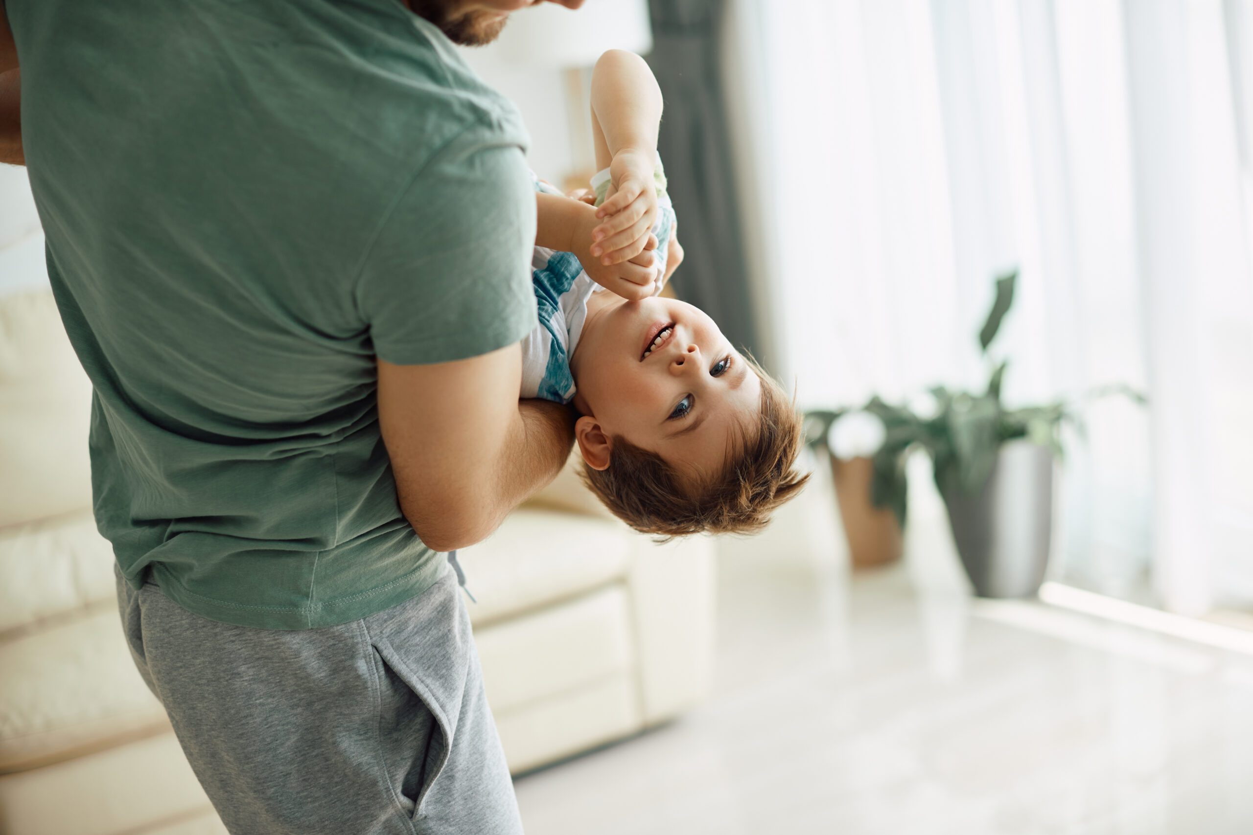 Niedliches Kind, das mit seinem verspielten Vater zu Hause Spaß hat.